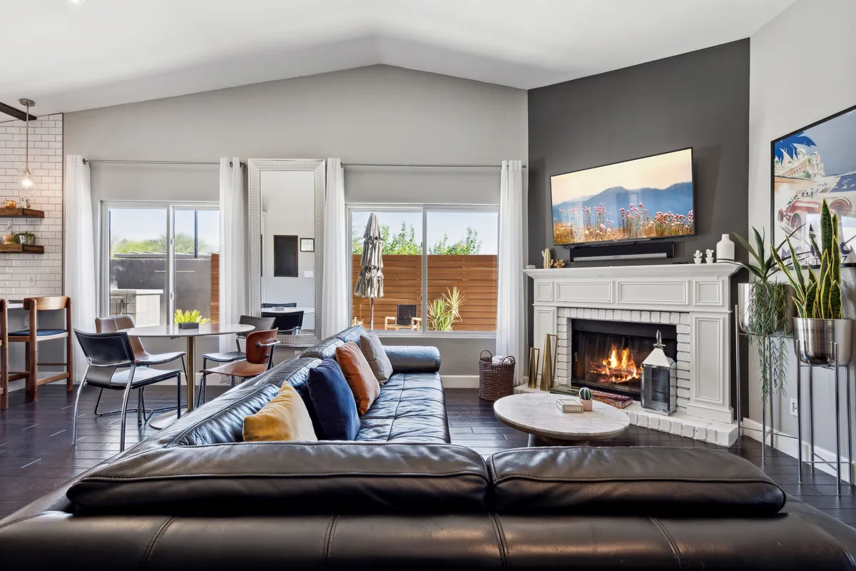 A cozy living room features a sofa with colorful cushions, a fireplace, and a television, providing a space perfect for families to relax, entertain, or enjoy quality time together.