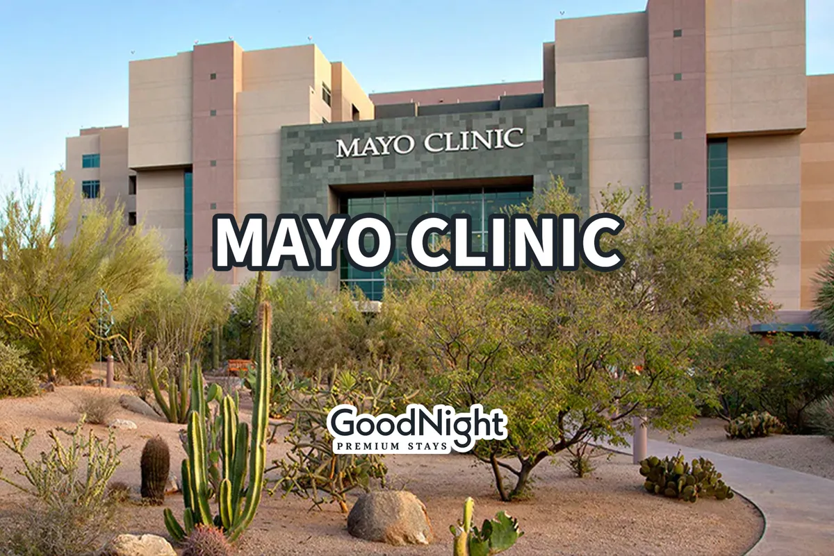 A wide exterior shot of the Mayo Clinic building surrounded by desert vegetation and a serene landscape. The modern medical facility is set against a peaceful backdrop, reflecting both convenience and tranquility.