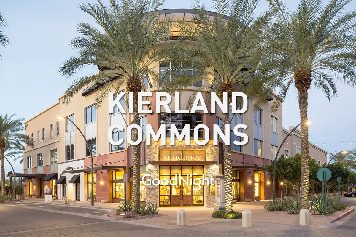A lively exterior shot of palm tree-lined storefronts and welcoming lighting fixtures, evoking the bustling atmosphere of nearby shopping and dining at Kierland Commons or Scottsdale Quarter. The vibe is vibrant and social, suggesting easy access to local attractions.