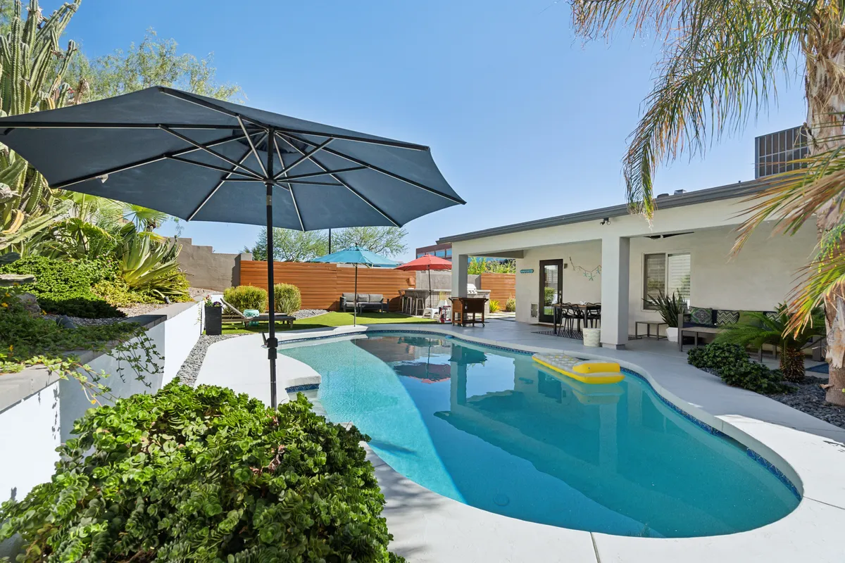 A stylish backyard scene featuring a sparkling swimming pool, shaded outdoor dining area, and lush greenery. The area is perfect for swimming, sunbathing, or evening gatherings, illustrating the relaxation and fun post-golf experiences described in the section.