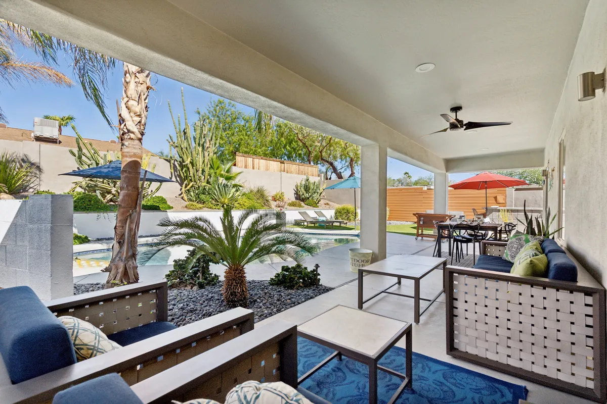 This exterior shot highlights the inviting pool area framed by palm trees and outdoor umbrellas. Lounge chairs are arranged for sunbathing and relaxation, and the seating arrangement encourages gatherings by the water.