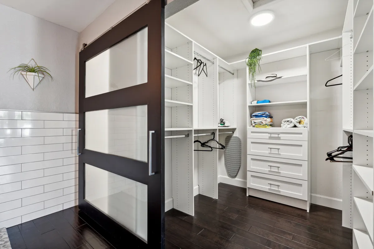 A tidy, organized interior space with sliding glass doors, open shelving, neatly folded towels, and hanging space for clothes. The design is practical and family-oriented, suggesting convenience for guests traveling with families or groups.