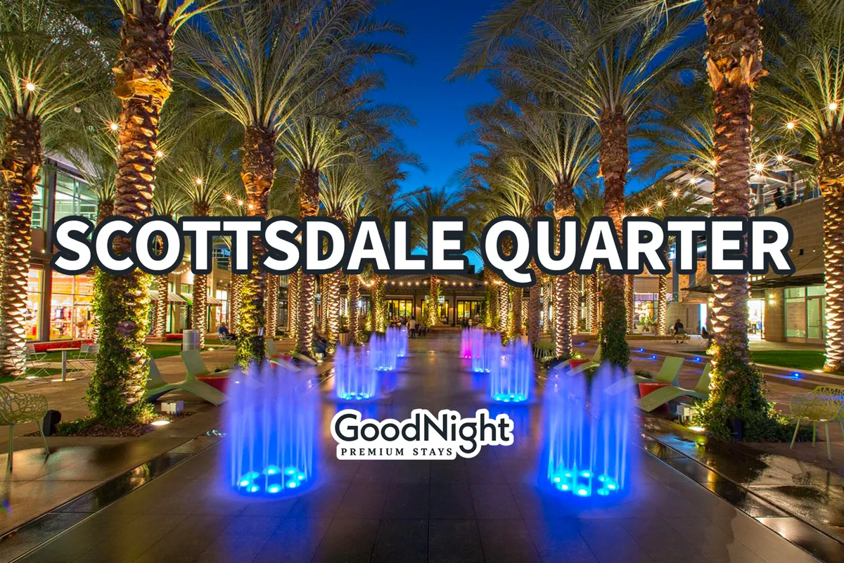 A vibrant night scene with colorful water fountains, palm trees, illuminated pathways, and modern architecture. The festive atmosphere evokes the upscale nightlife, shopping, and dining opportunities nearby in Scottsdale.
